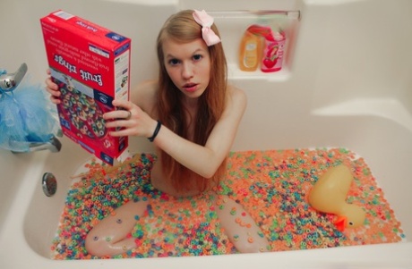 Молодо выглядящая девушка Долли Литтл высыпает коробку хлопьев в воду для ванны 2