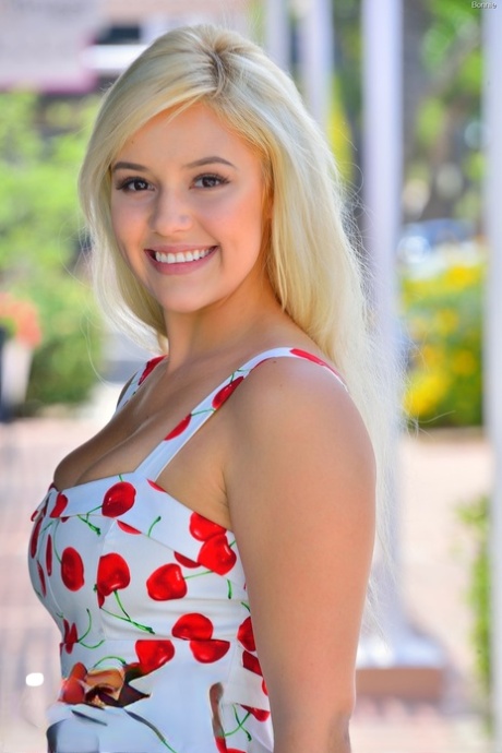 Симпатичная блондинка приподнимает короткое платье, обнажая верхнюю юбку, и теребит пальцами лысую киску снаружи 4